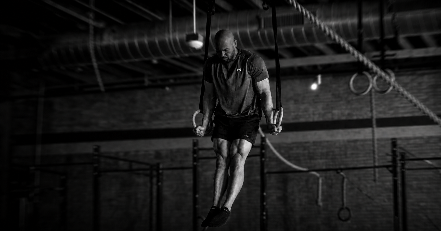 Coach Justin Casipit holding a strong support position on gymnastics rings